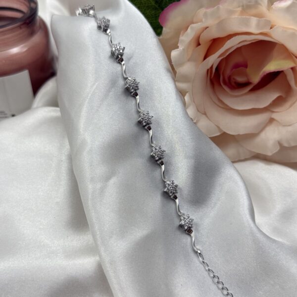 Elegantna srebrna narukvica sa nizom cvjetića optočenih cirkonima na bijelom satenu - Zlatara Čehajjić