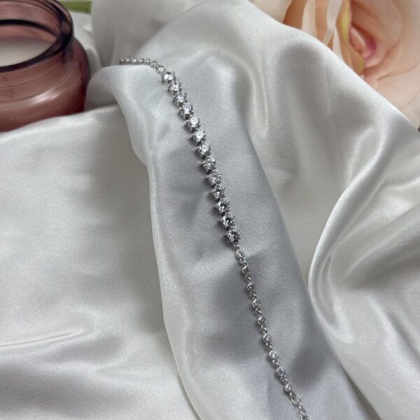 Elegantna srebrna narukvica sa krupnijim centralnim cirkonima na bijeloj satenskoj podlozi