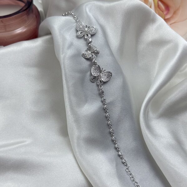 Elegantna srebrna narukvica sa tri leptira prekrivena cirkonima na bijeloj satenskoj podlozi